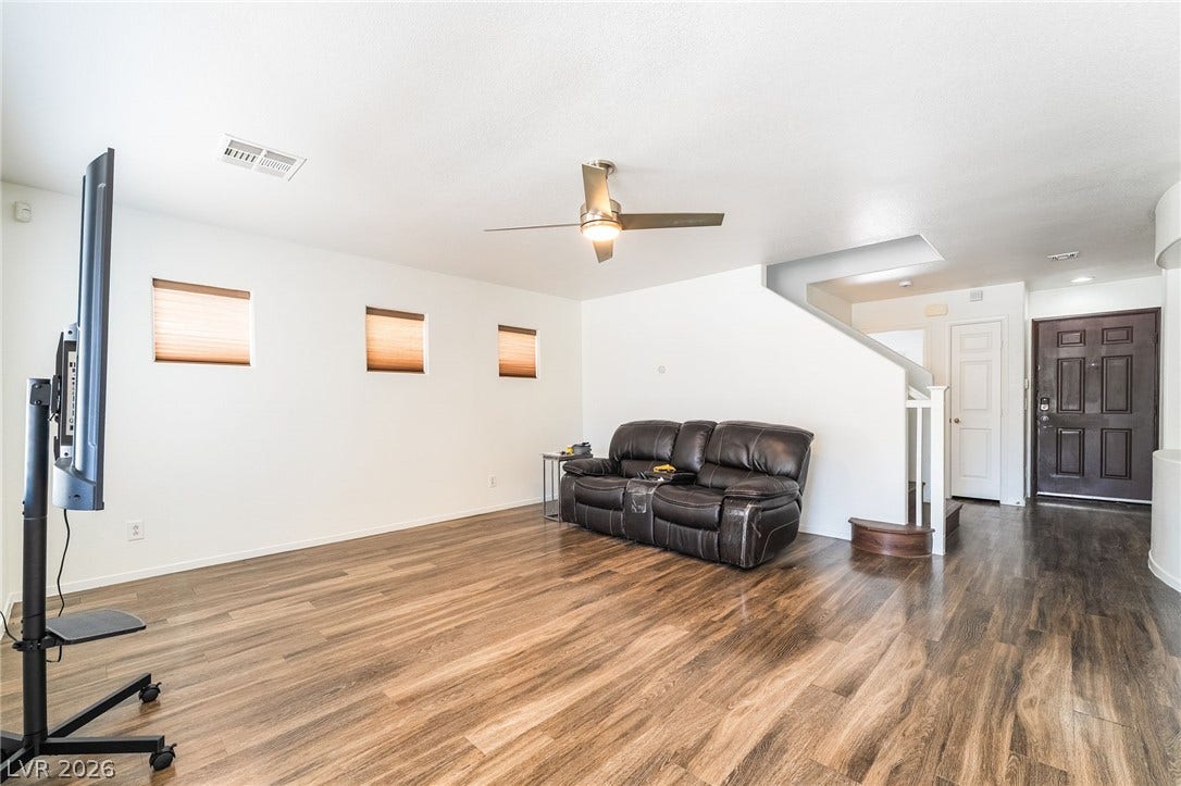 6275 Felicitas Avenue, Las Vegas, NV 89122 Rich wood-look flooring anchors this open living space, leading past stairs toward the entry.