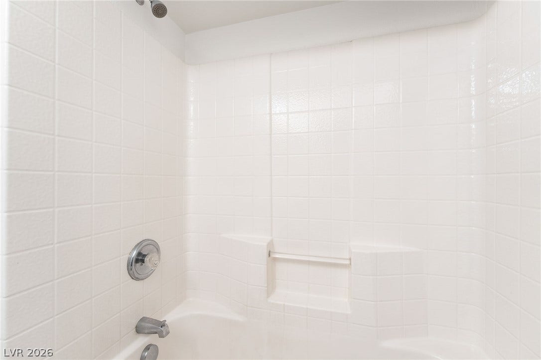 6275 Felicitas Avenue, Las Vegas, NV 89122 Clean square tiling surrounds a classic tub and shower combination with integrated shelving.