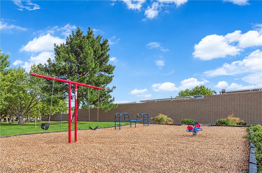 3753 Heritage Avenue, Las Vegas, NV 89121 Mature trees border a spacious outdoor play area set against a clear blue sky.