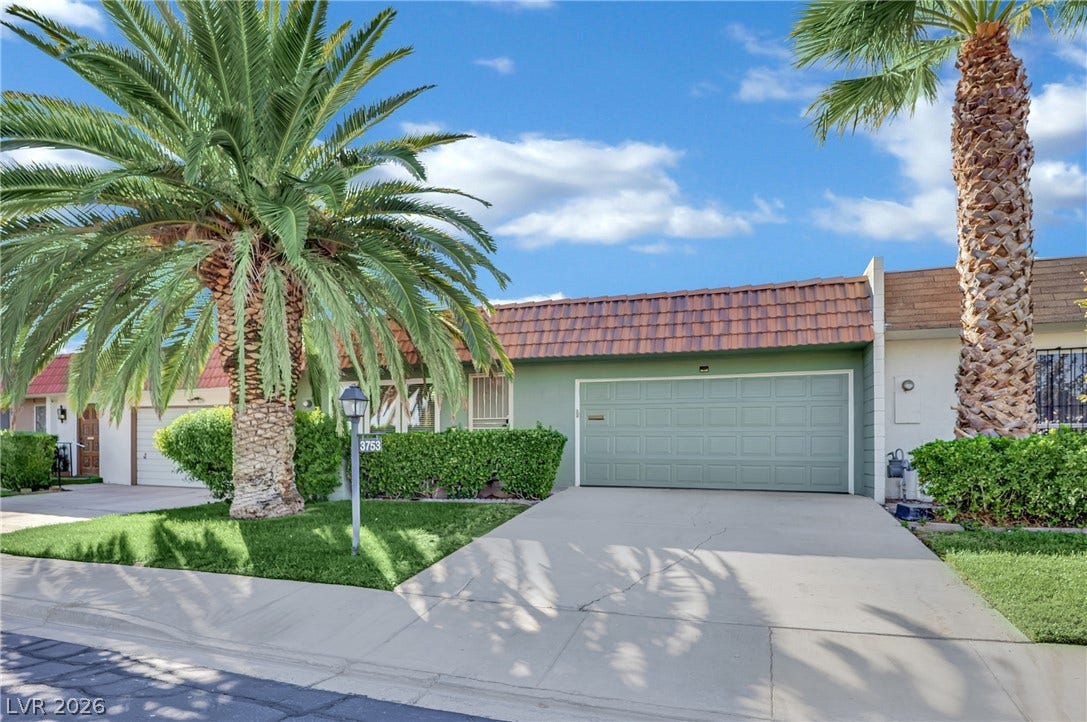 3753 Heritage Avenue, Las Vegas, NV 89121 A spacious concrete driveway leads directly to an attached garage beneath a classic tiled roofline.