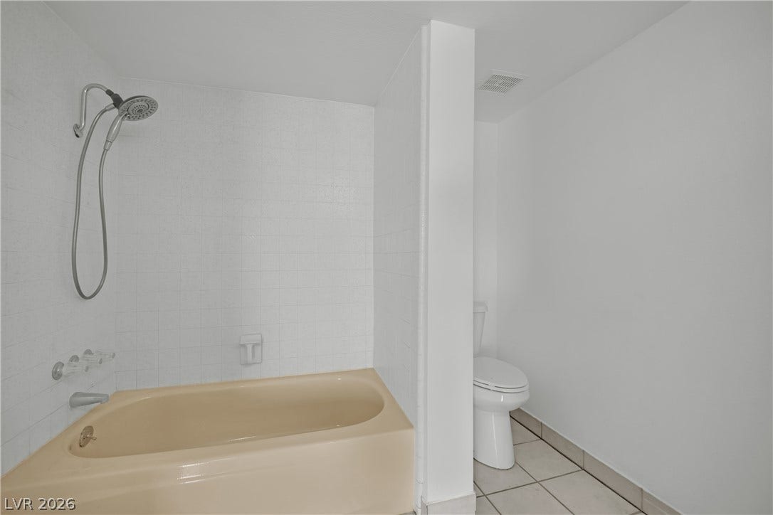 3753 Heritage Avenue, Las Vegas, NV 89121 Tiled walls frame the soaking tub and private commode alcove in this functional bathroom.