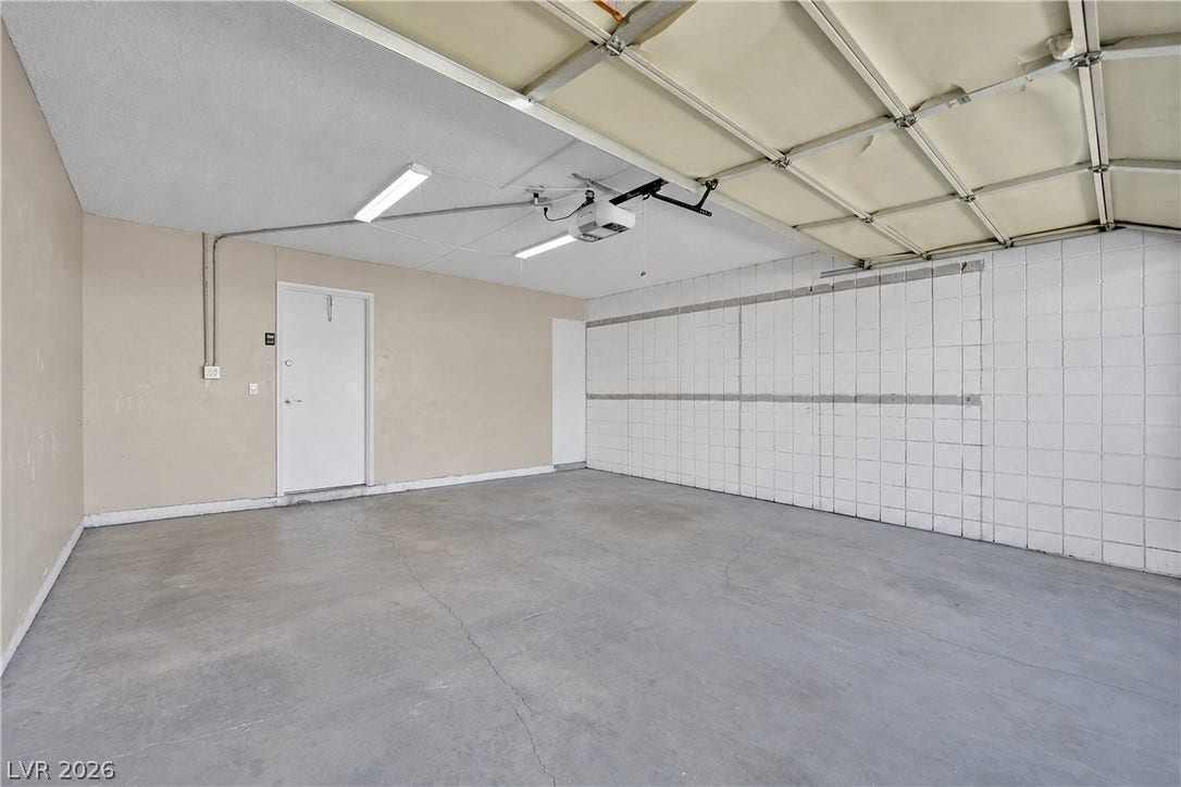 3753 Heritage Avenue, Las Vegas, NV 89121 A spacious garage features durable concrete flooring, textured block walls, and an overhead door.