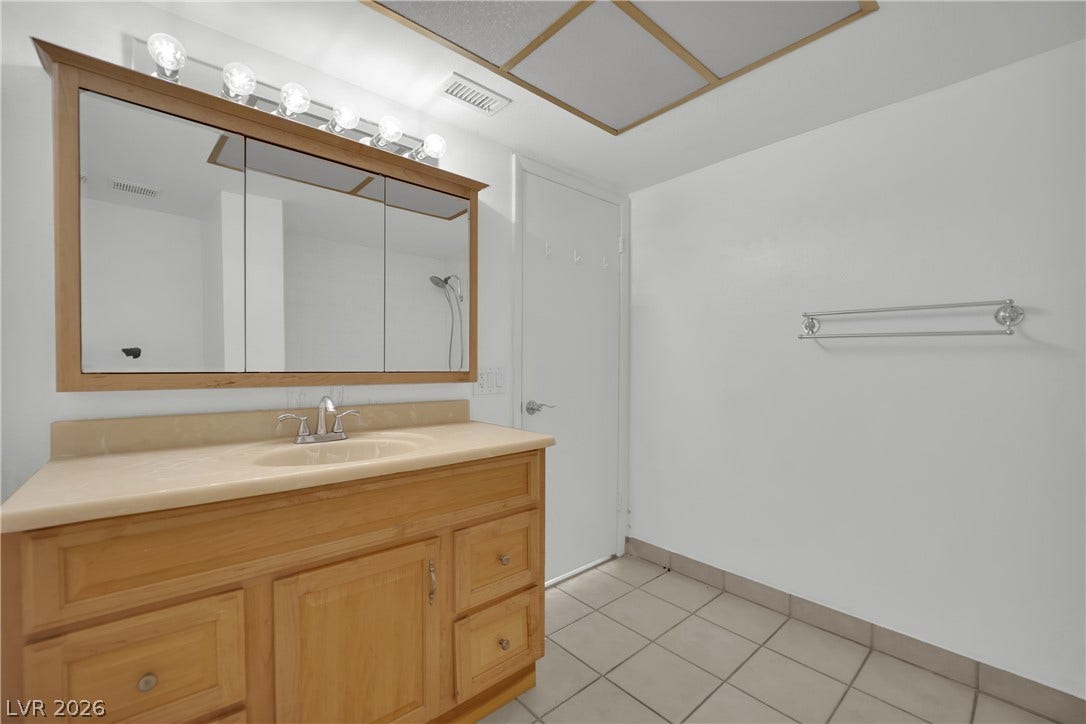 3753 Heritage Avenue, Las Vegas, NV 89121 Tiled flooring and a spacious wood vanity complete this functional bathroom space.
