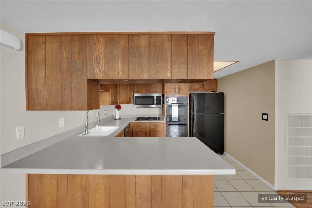 3753 Heritage Avenue, Las Vegas, NV 89121 Rich wood cabinetry surrounds a peninsula overlooking a functional tiled floor workspace.