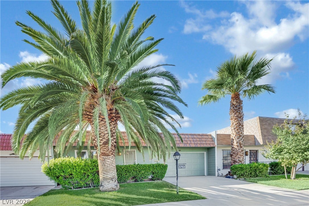 3753 Heritage Avenue, Las Vegas, NV 89121 Towering palm trees frame the concrete driveway leading to the single-level home.