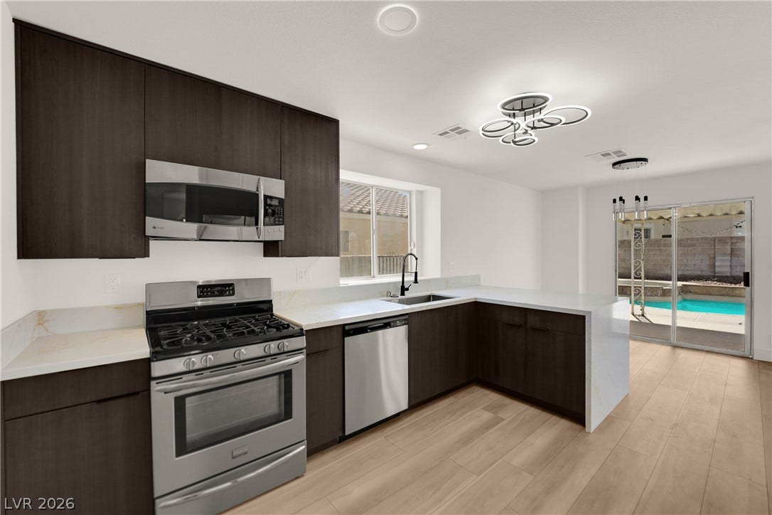 Crisp white stone countertops contrast beautifully with rich cabinetry and light wood-plank flooring.