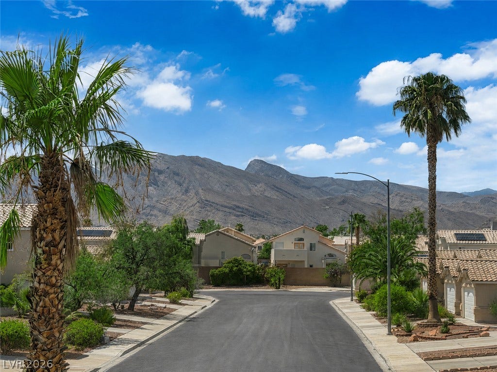 Dramatic mountain vistas rise above this quiet residential street framed by towering palm trees.