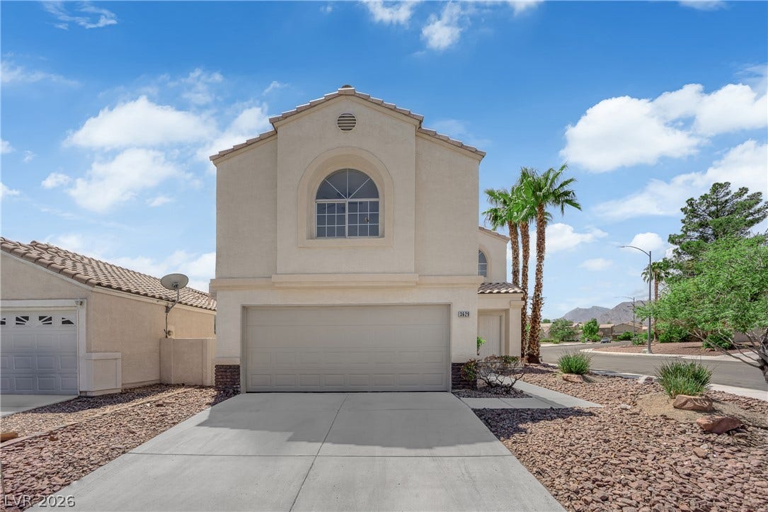 An arched statement window and tiled roof define this stucco home's exterior.
