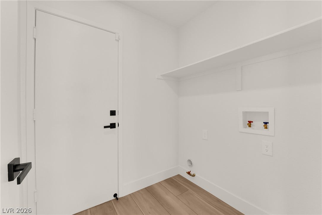 A tidy utility space featuring durable wood flooring and integrated wall-mounted storage shelves.