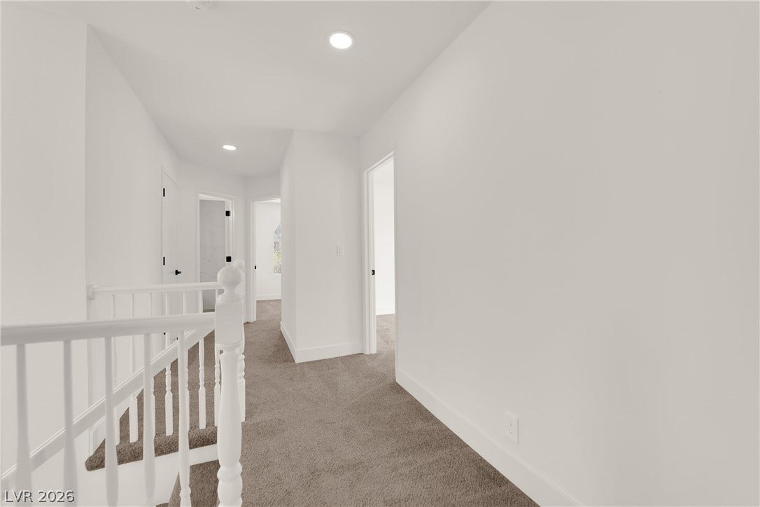 Crisp walls and plush carpeting line this upper-level hallway leading to multiple rooms.