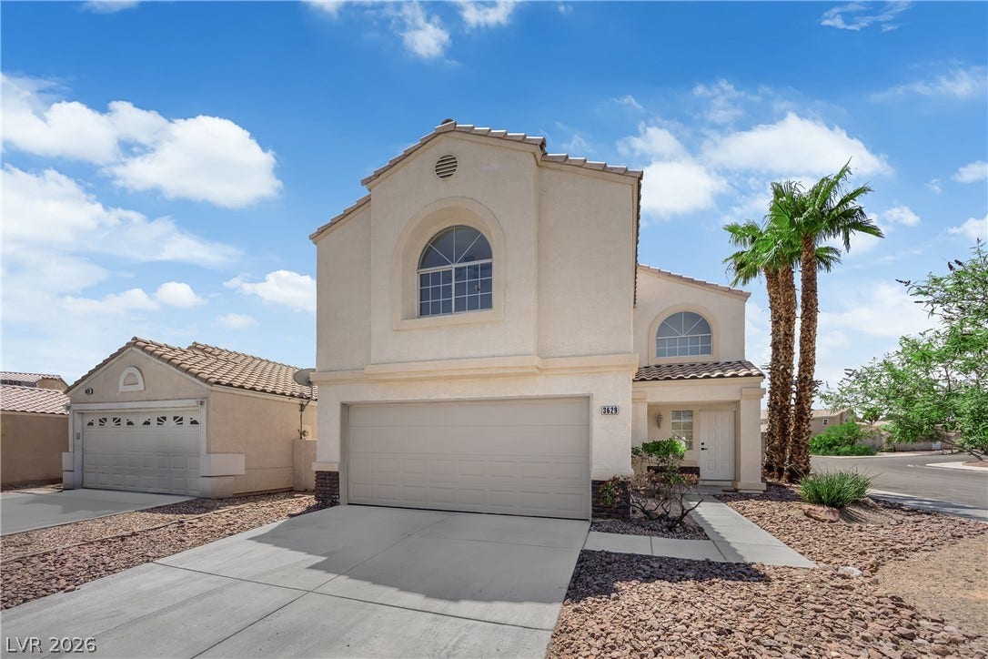 An inviting exterior features a stucco facade and arched windows framed by towering palm trees.