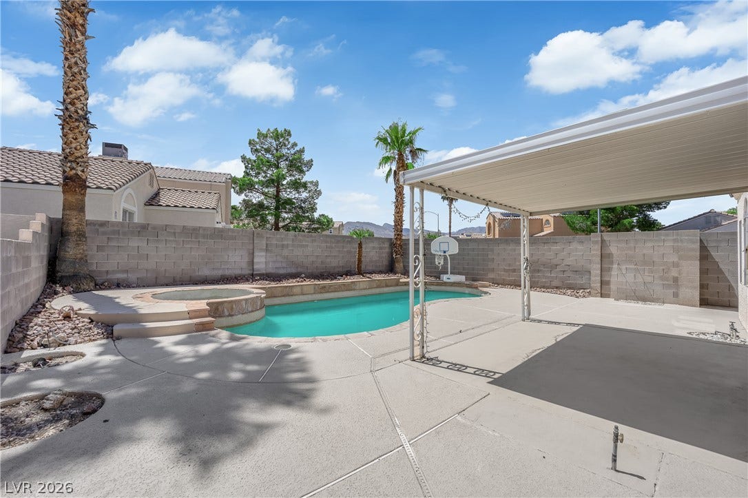 A spacious covered patio overlooks the private backyard pool and integrated spa.