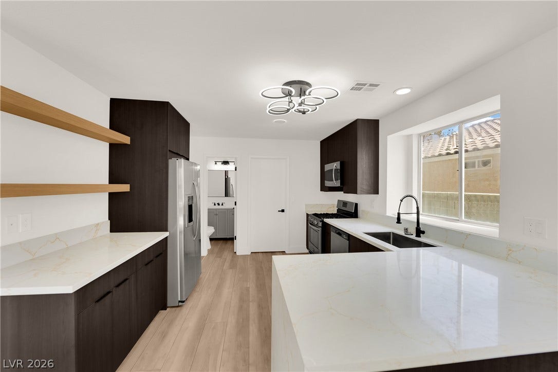 Rich dark cabinetry contrasts beautifully with gleaming stone countertops and natural wood floors.