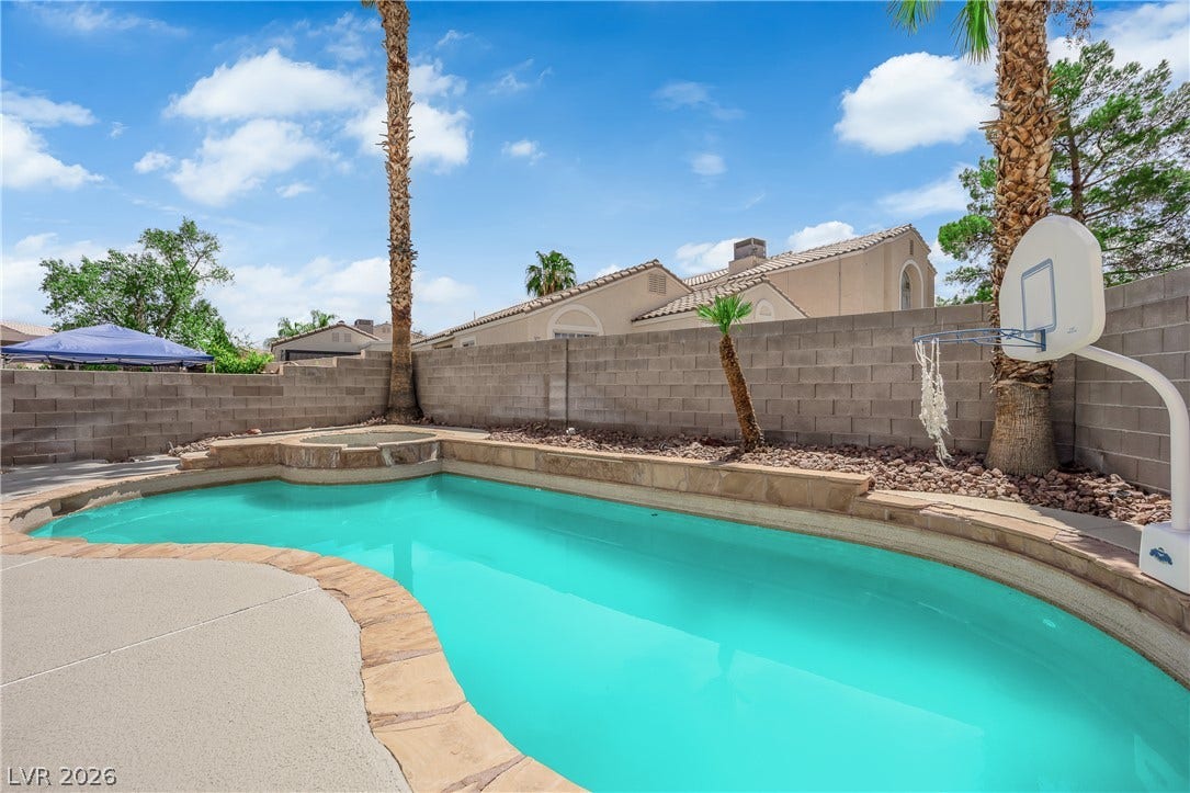 A private swimming pool and integrated spa sit surrounded by stone coping and block walls.