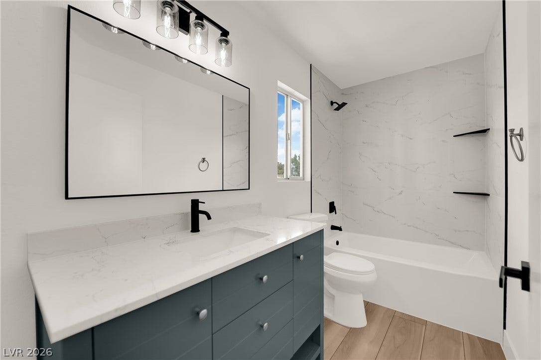 Modern stone countertops and wood flooring highlight this updated washroom space.