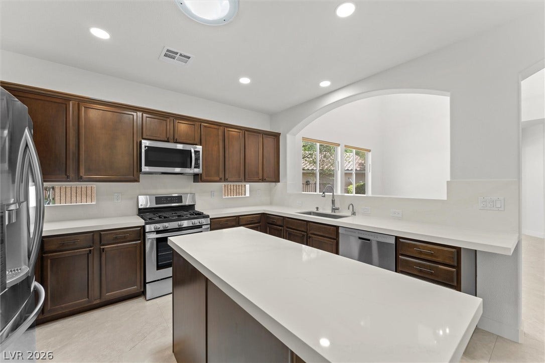 215 Sunset Shower Drive, Henderson, NV 89012 Rich wood cabinetry contrasts beautifully with sleek white countertops and a central island.