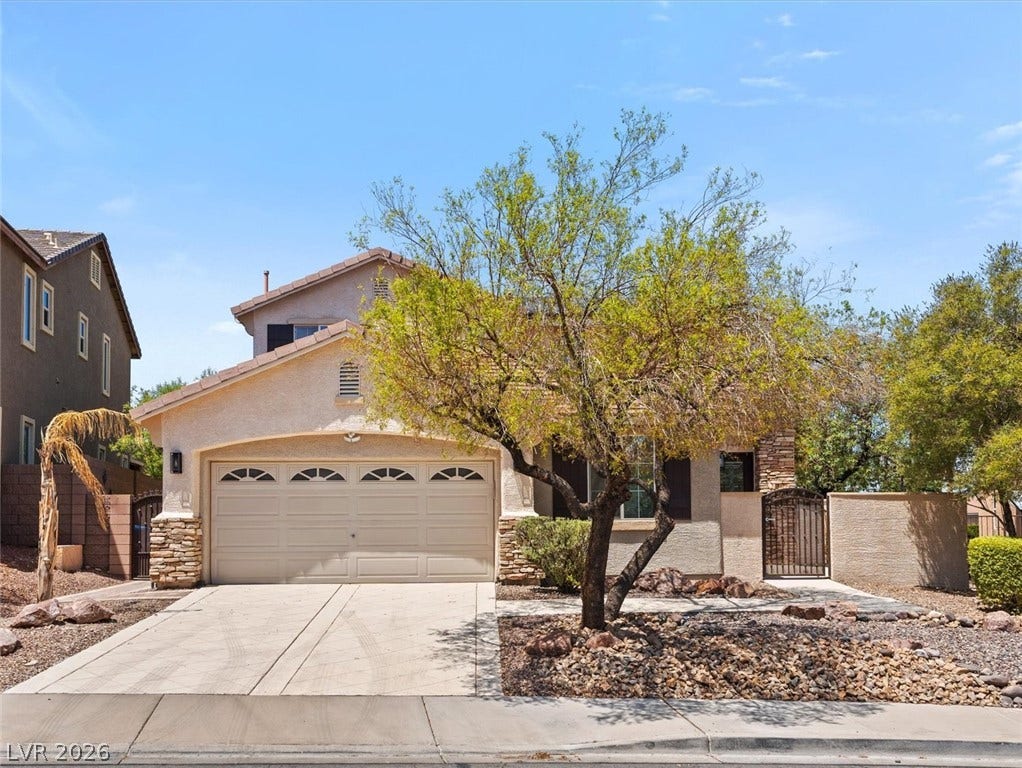 215 Sunset Shower Drive, Henderson, NV 89012 A spacious driveway leads to the attached garage under tile roofing and stucco siding.