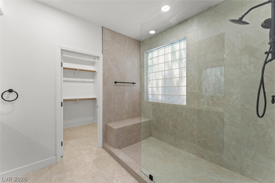 215 Sunset Shower Drive, Henderson, NV 89012 Sleek tile finishes and a spacious walk-in shower define this modern primary bath design.