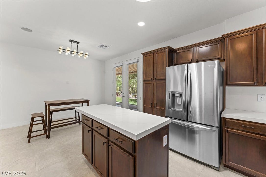 215 Sunset Shower Drive, Henderson, NV 89012 Rich wood cabinetry contrasts beautifully with white solid-surface countertops in this bright culinary space.