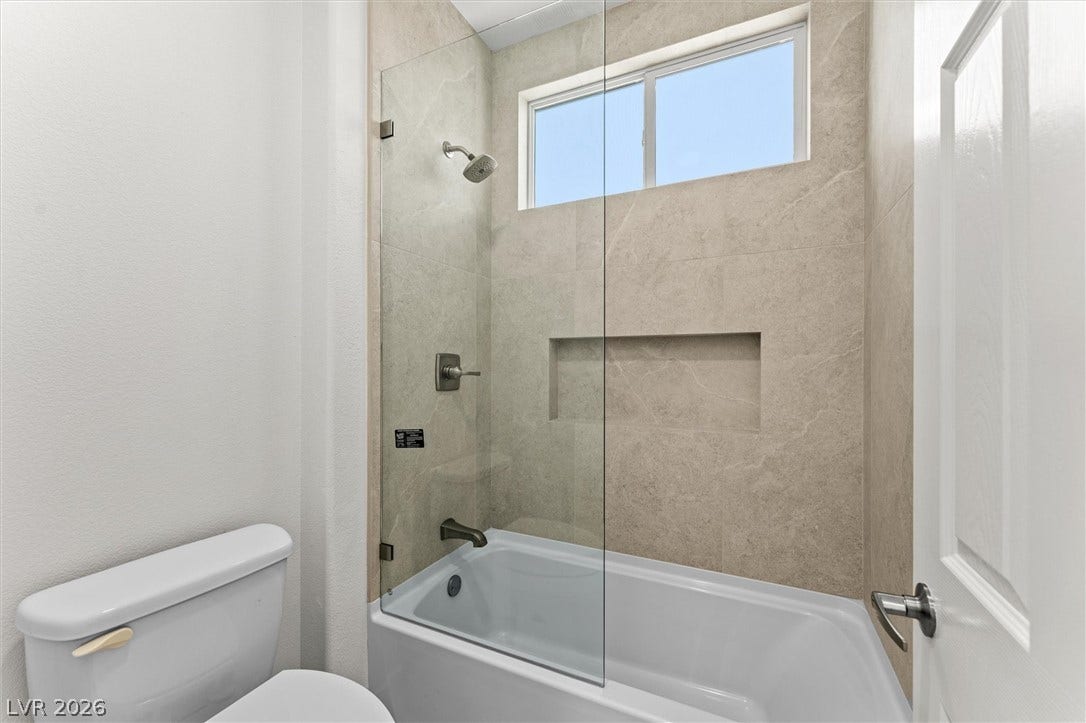 215 Sunset Shower Drive, Henderson, NV 89012 Tiled shower walls surround a built-in bathtub beneath a high window.