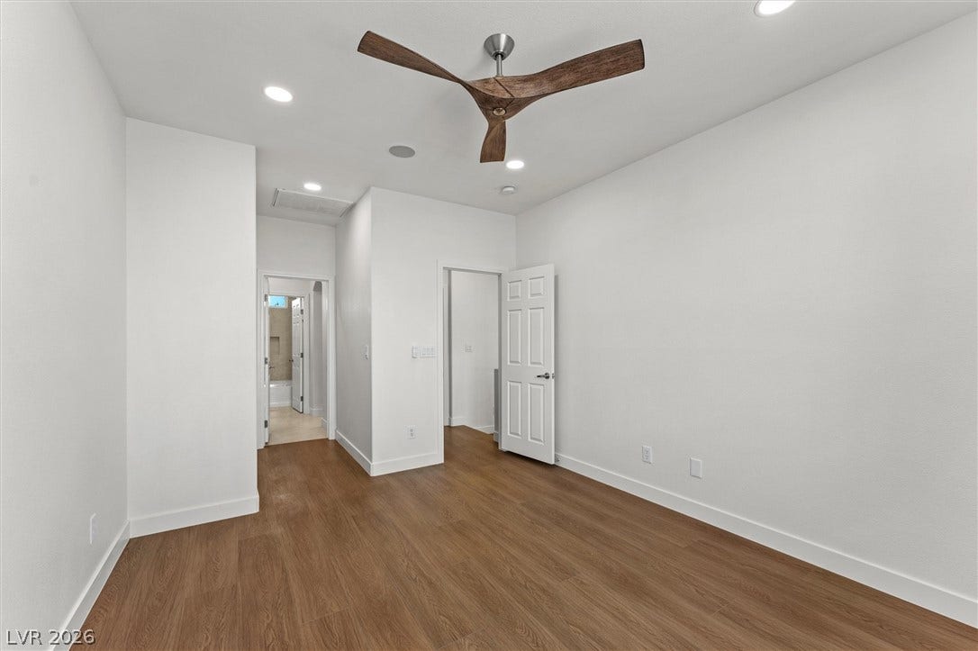 215 Sunset Shower Drive, Henderson, NV 89012 Gleaming wood-look floors pair beautifully with crisp white walls in this versatile bedroom.