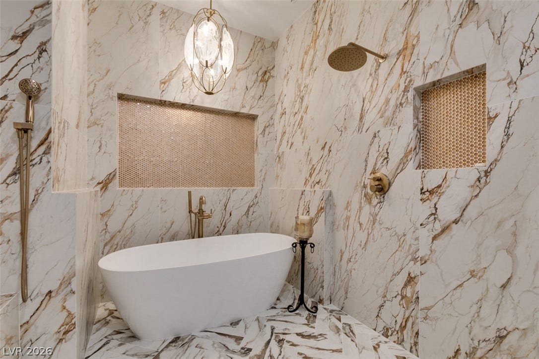 2532 Faiss Drive, Las Vegas, NV 89134 Floor-to-ceiling marble tile surrounds a freestanding soaking tub in this luxurious bathroom.