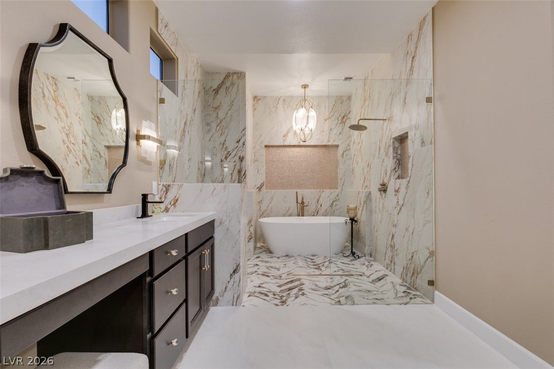 2532 Faiss Drive, Las Vegas, NV 89134 Elegant stone surrounds elevate this refined primary bathroom featuring a freestanding tub and glass shower.