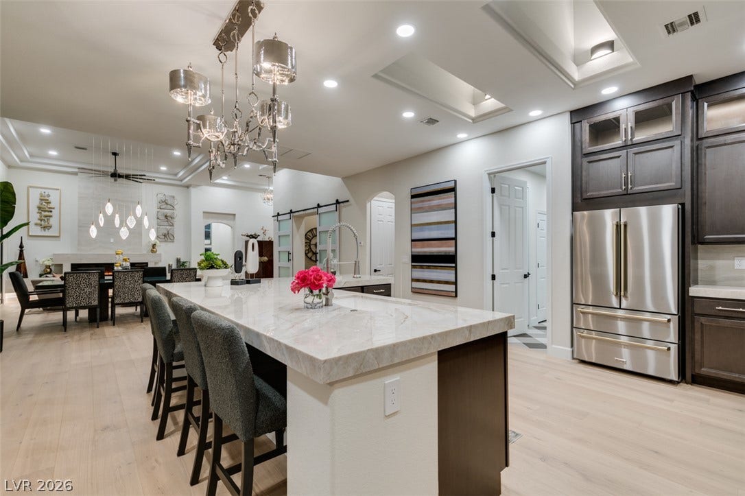 2532 Faiss Drive, Las Vegas, NV 89134 Polished stone countertops and seamless wooden flooring ground this airy kitchen layout.