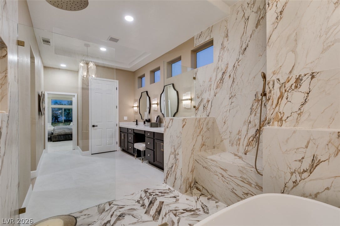 2532 Faiss Drive, Las Vegas, NV 89134 Elegant stone finishes and high ceilings define this expansive, modern primary bathroom suite.