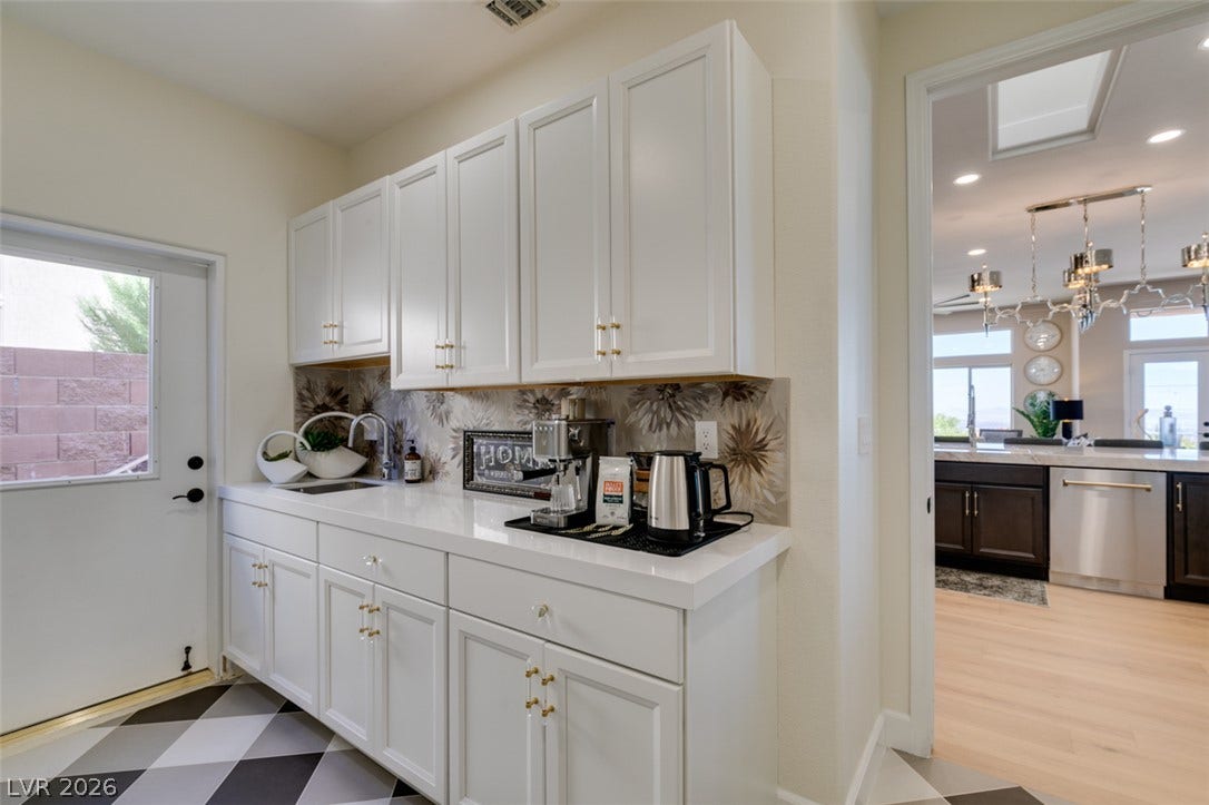 2532 Faiss Drive, Las Vegas, NV 89134 White cabinetry and stone counters create a functional preparation station adjacent to the main kitchen.