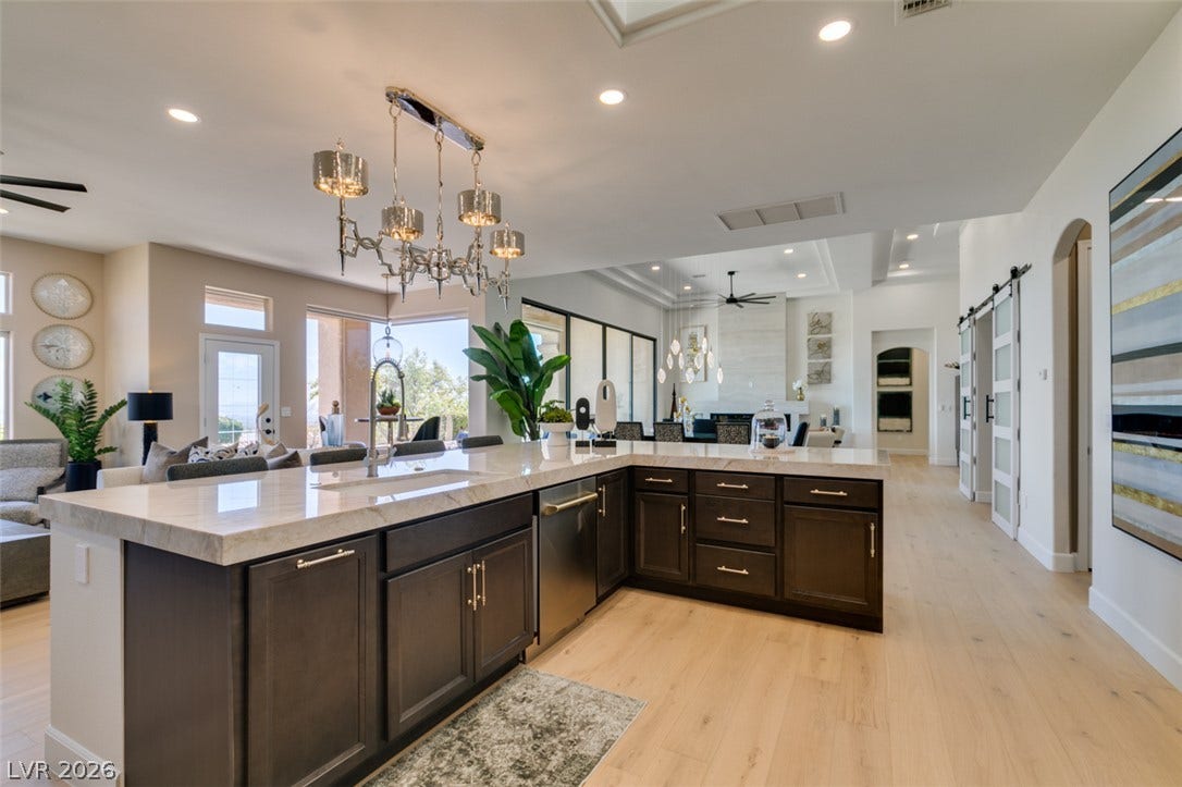2532 Faiss Drive, Las Vegas, NV 89134 Gleaming stone counters and wide plank flooring define this expansive culinary and living zone.