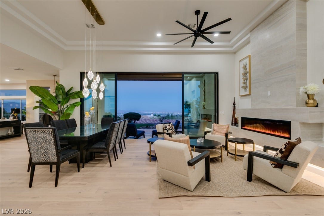 2532 Faiss Drive, Las Vegas, NV 89134 A modern fireplace anchors the open-concept living area under tray ceilings and wide glass doors.