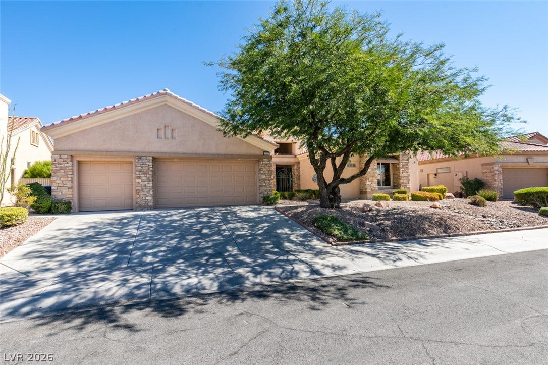 2532 Faiss Drive, Las Vegas, NV 89134 A spacious driveway leads to this single-story desert home featuring stone accents and tile roofing.
