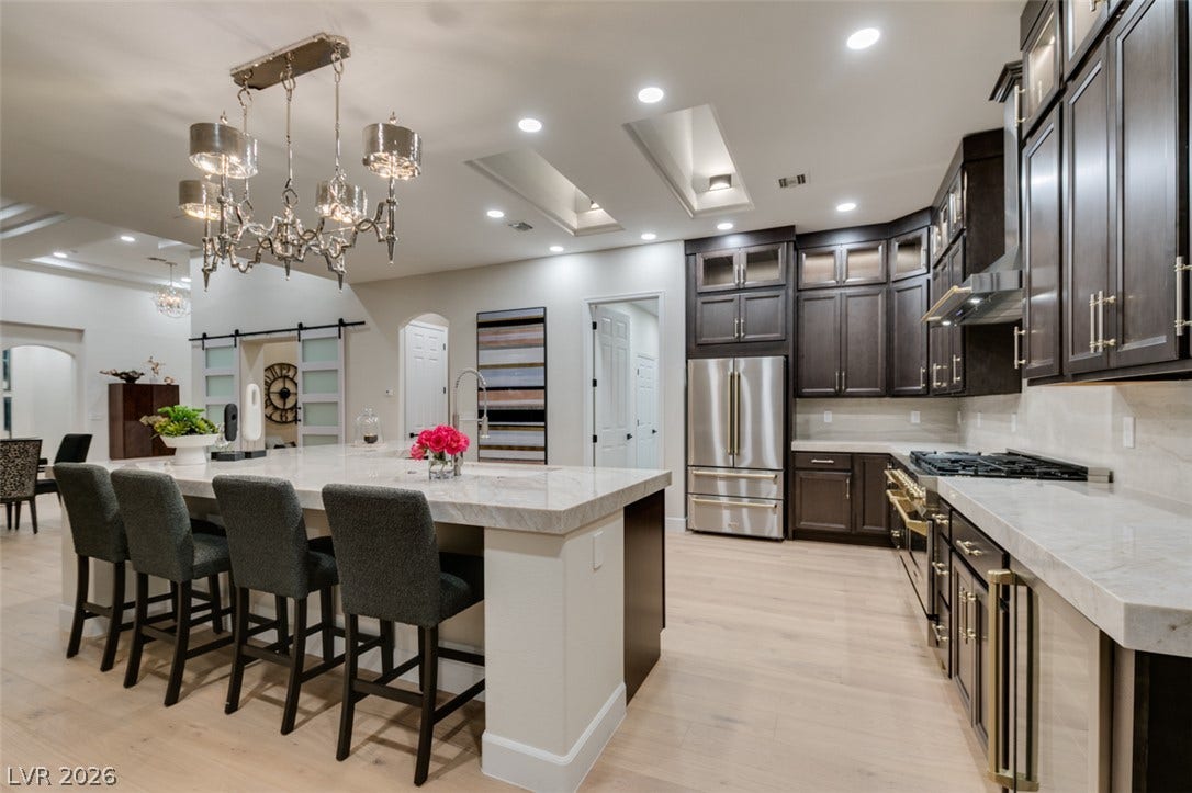 2532 Faiss Drive, Las Vegas, NV 89134 Gleaming stone countertops and dark cabinetry anchor this modern kitchen with light hardwood flooring.