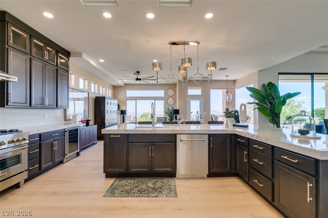 2532 Faiss Drive, Las Vegas, NV 89134 Premium dark cabinetry, expansive stone countertops, and light hardwood flooring define this gourmet culinary space.
