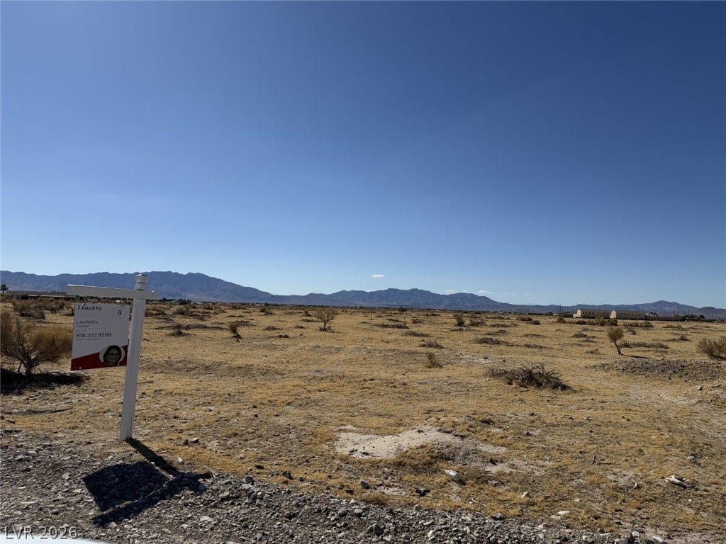 An expansive desert lot presents a blank slate with majestic mountain ranges in the distance.