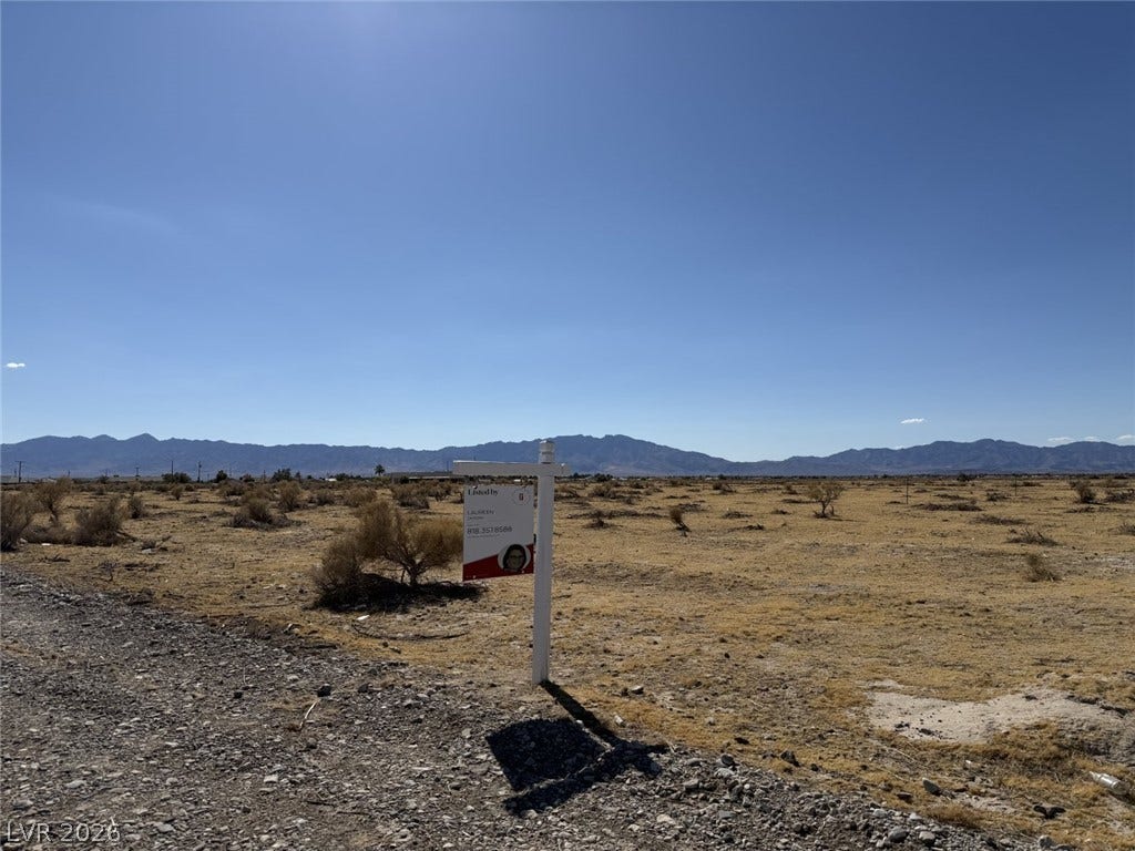 Vast desert acreage unfolds beneath clear blue skies with dramatic mountain silhouettes on the horizon.