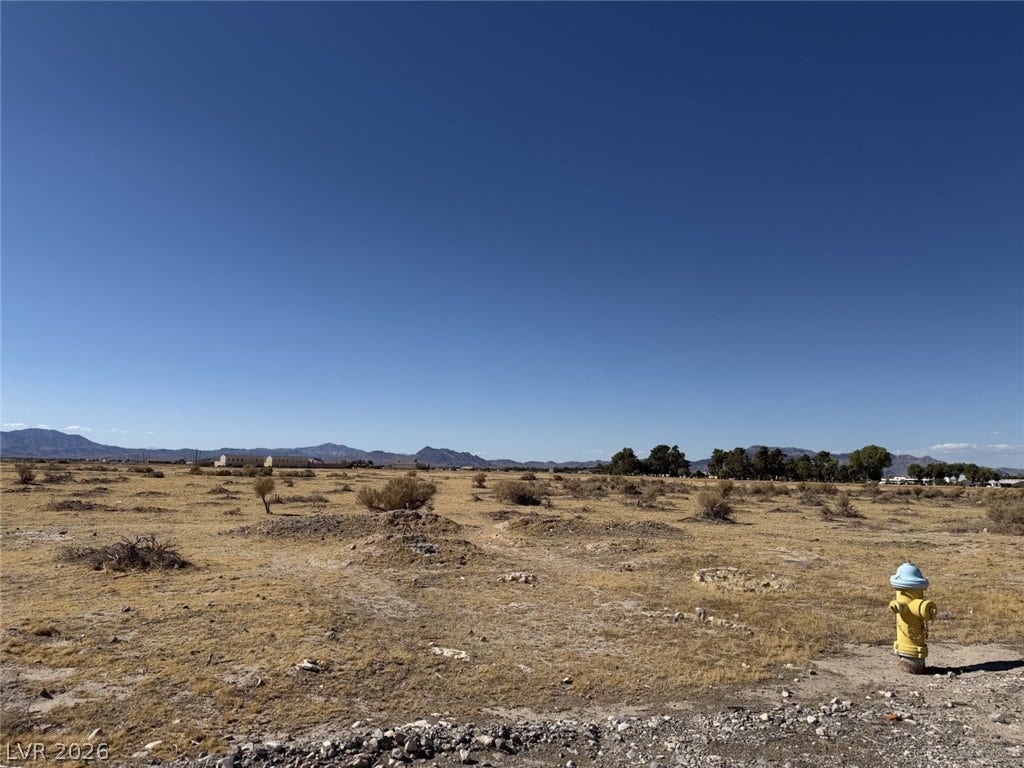 Distant mountains frame this open parcel of land under a clear blue sky.