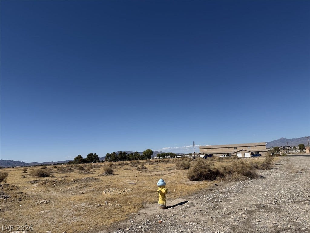 An open desert parcel offers sweeping views of distant mountain ranges under clear skies.