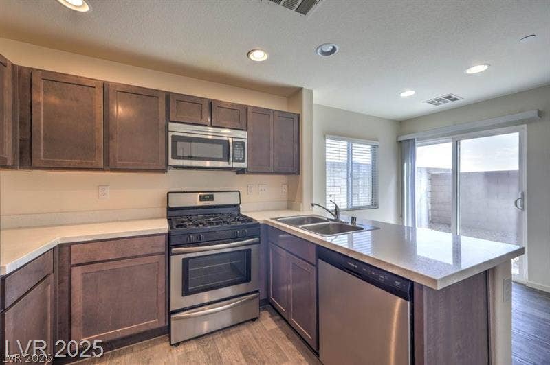 4134 San Cuervo Way, Las Vegas, NV 89115 Gleaming stone countertops and matching cabinetry surround a modern cooking area next to sliding glass doors.