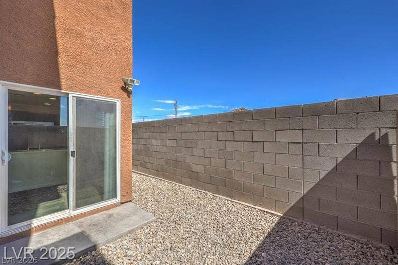 4134 San Cuervo Way, Las Vegas, NV 89115 Sliding glass doors open directly to a private, low-maintenance gravel courtyard enclosed by block fencing.