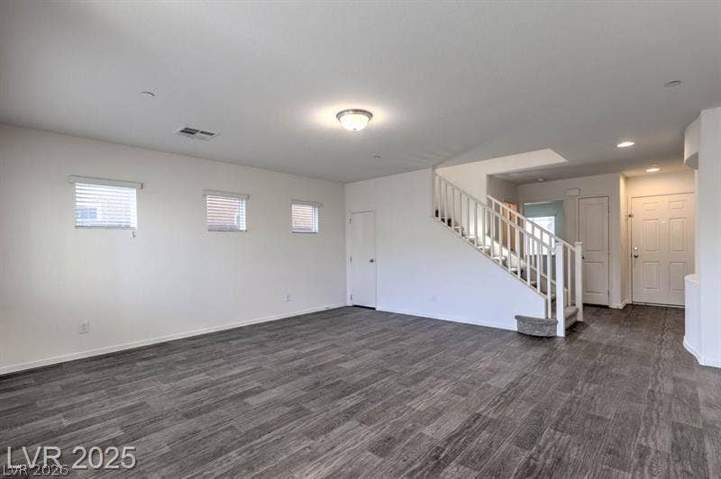 4134 San Cuervo Way, Las Vegas, NV 89115 An open floorplan showcases durable plank flooring and a prominent staircase leading upstairs.