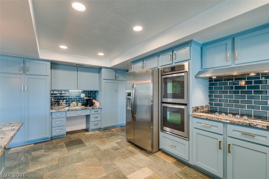 2246 Almart Circle, Henderson, NV 89014 Richly textured stone tile flooring grounds custom cabinetry and stainless steel appliances in this kitchen.