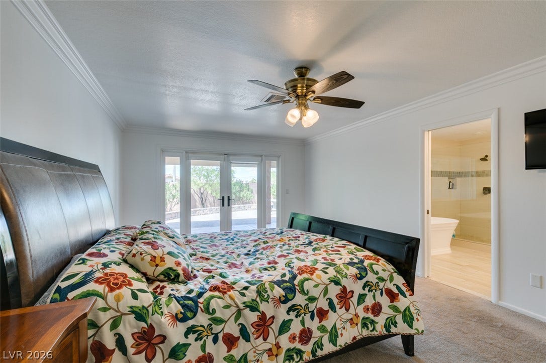 2246 Almart Circle, Henderson, NV 89014 Double doors open to the patio from this peaceful bedroom featuring an adjacent bathroom.