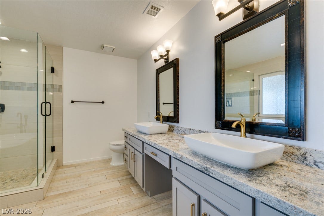 2246 Almart Circle, Henderson, NV 89014 Double vessel sinks rest on granite countertops alongside a glass-enclosed walk-in shower.