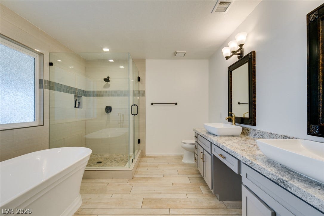 2246 Almart Circle, Henderson, NV 89014 Polished stone counters and wood-look tile floors define this elegant primary bath.