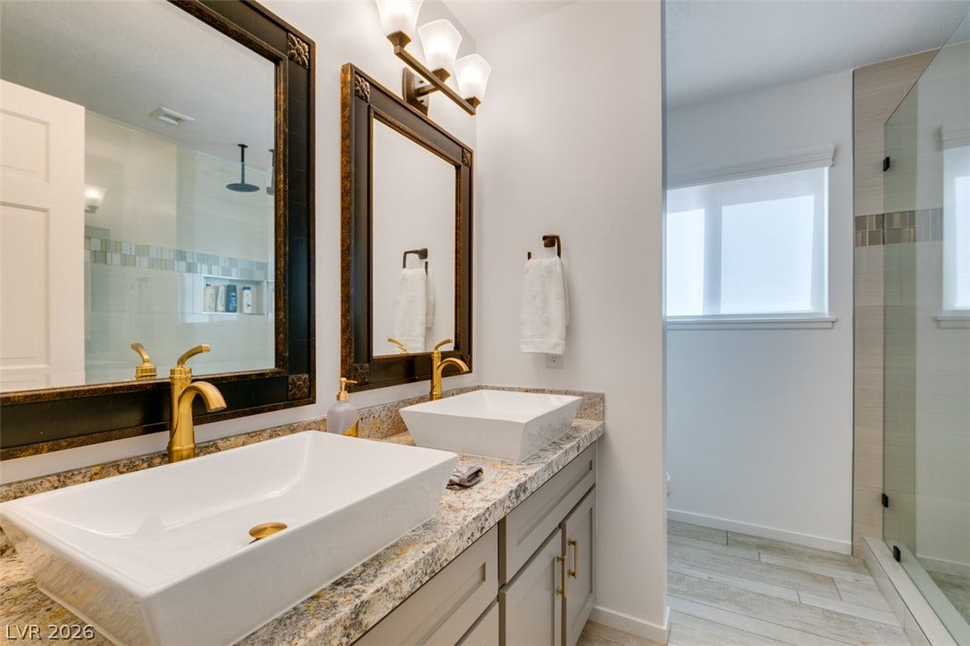 2246 Almart Circle, Henderson, NV 89014 Ornate framed mirrors and vessel sinks accent a modern vanity with stone counters.