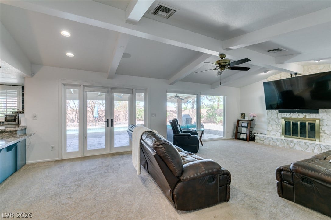 2246 Almart Circle, Henderson, NV 89014 Beamed ceilings and a stone fireplace anchor this comfortable living room opening to the pool.
