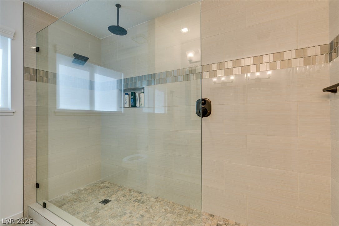2246 Almart Circle, Henderson, NV 89014 Floor-to-ceiling wall tile and a mosaic stone floor elevate this modern walk-in shower.