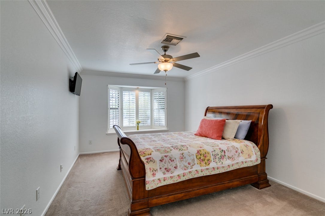 2246 Almart Circle, Henderson, NV 89014 Crown molding frames this comfortable bedroom featuring a classic bay window and neutral carpeting.